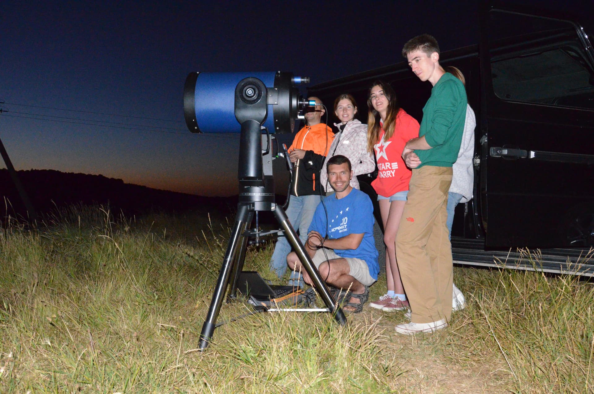 A small group gathered around the telescope at dusk